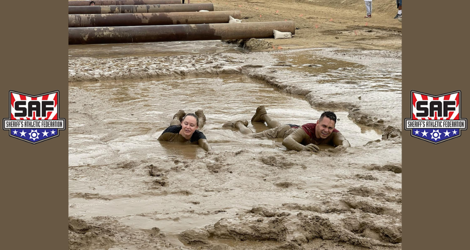Chief of Staff Claire Cozad and Sheriff's Department Specialist Dillon Levosky low crawl through the mud.