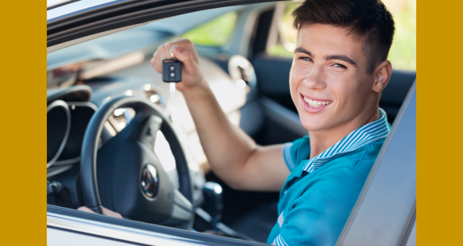 Teenaged young man smiles while sitting in the driver's seat of a car.