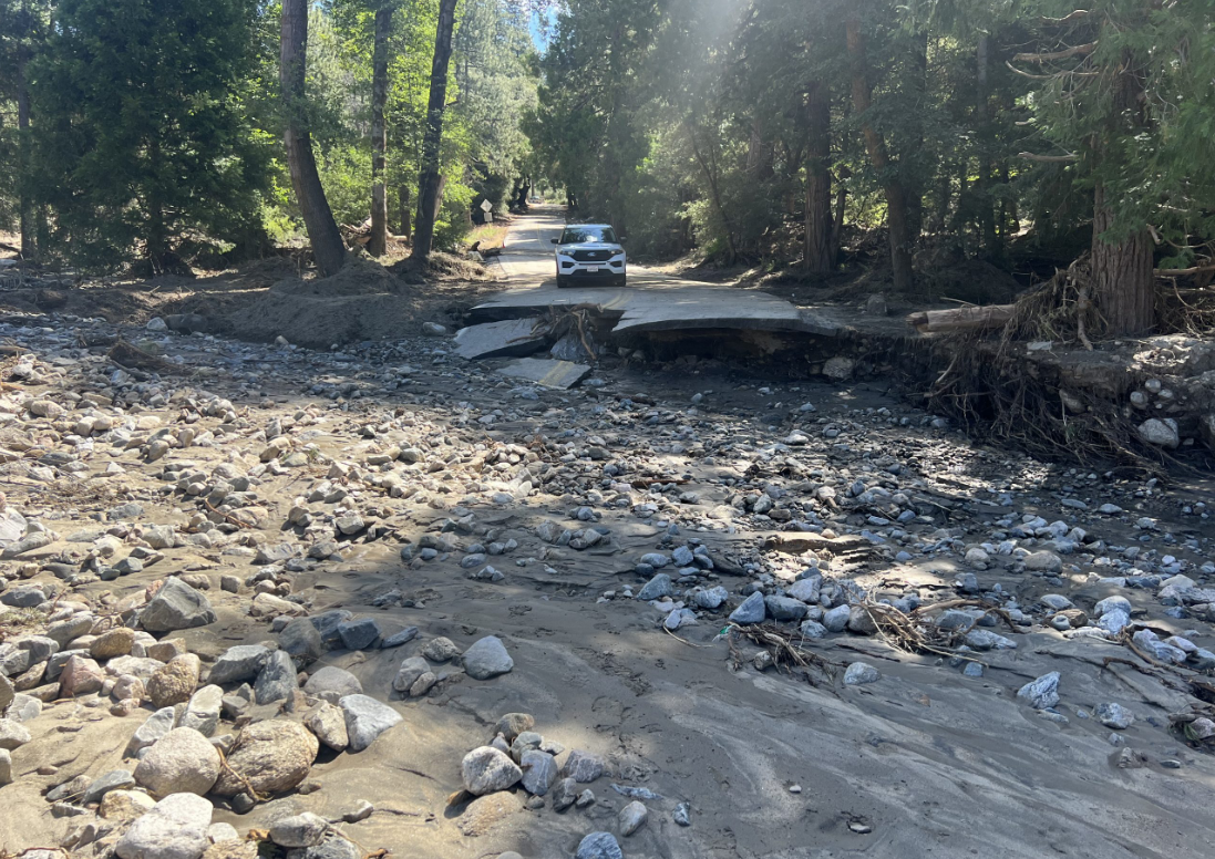 A car parked in front of a washed out road in Seven Oaks.