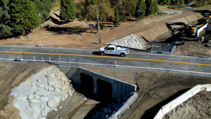A white truck drives across the fully repaired Birch Creek Bridge in Oak Glen, CA.
