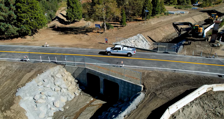 A white truck drives across the fully repaired Birch Creek Bridge in Oak Glen, CA.
