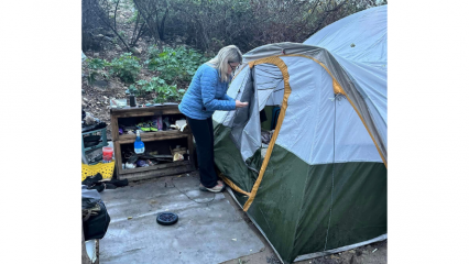 Supervisor Dawn Rowe looks inside a tent occupied by a homeless individual in Highland.