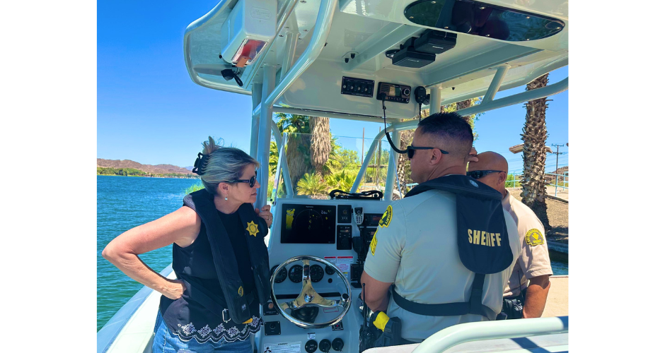 Supervisor Rowe stands on a boat on the Colorado River near Needles, listening to members of the Sheriff's Marine Enforcement Team discuss their operation.