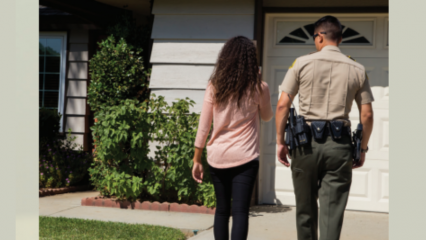 A county resident has a conversation with a Sheriff's Department representative while walking back to a house.