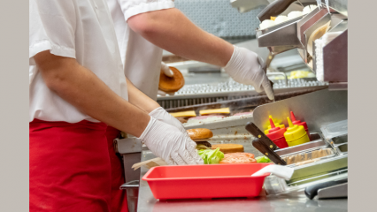 Two workers assembling hamburgers in a restaurant kitchen.