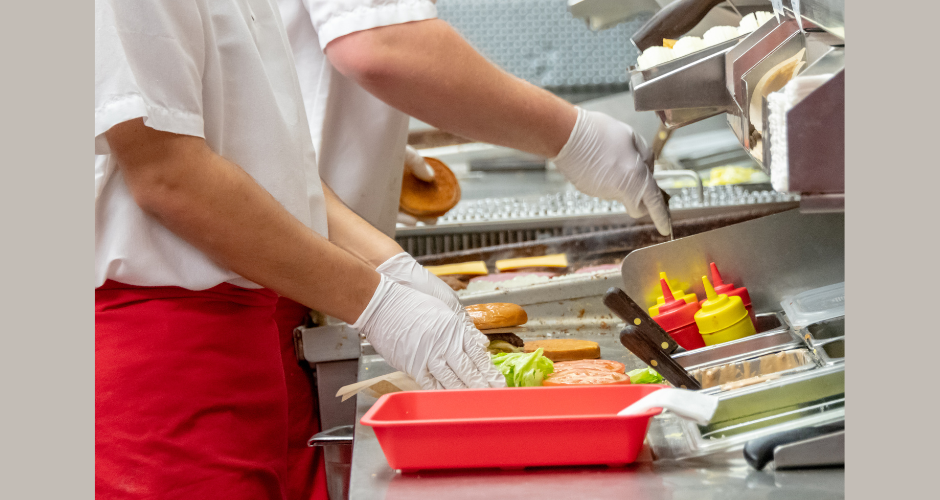 Two workers assembling hamburgers in a restaurant kitchen.