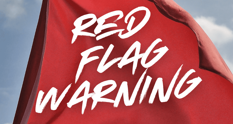 A red flag blowing in the wind with the words RED FLAG WARNING