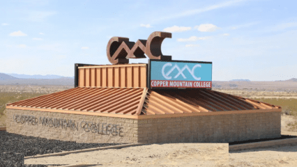 Copper Mountain College's gateway entry sign sits on a sunny summer day in Joshua Tree