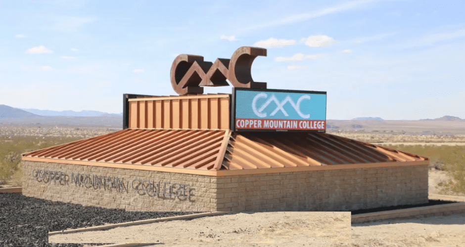 Copper Mountain College's gateway entry sign sits on a sunny summer day in Joshua Tree