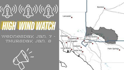 Split graphic announcing a High Wind Watch for Wednesday, Jan. 7 through Thursday, Jan. 8. The left side shows alert bell icons, the words “High Wind Watch,” and a megaphone graphic on a gray background. The right side displays a map of Southern California highlighting affected areas in San Bernardino County, with nearby cities including San Bernardino, Riverside, Barstow, Los Angeles, and Palm Springs labeled.