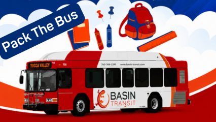 Illustration promoting the "Pack the Bus" school supply drive featuring a red-and-white Basin Transit bus labeled "Yucca Valley" beneath floating school supplies, including a backpack, notebooks, crayons, ruler, and push pins. A blue banner in the upper left reads "Pack The Bus," with a red, white, and blue background accented by clouds.