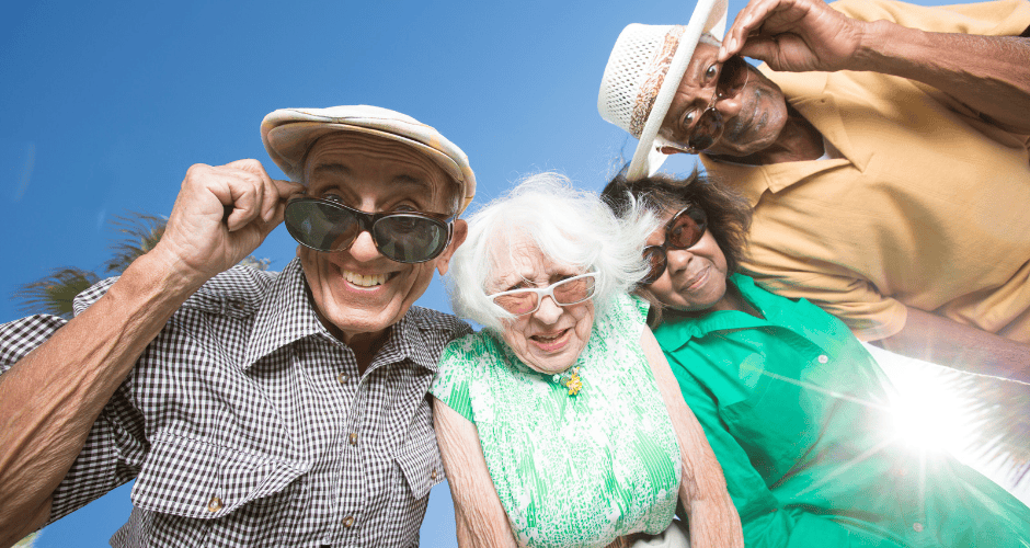 Four older adults look down towards the camera while smiling on a sunny day
